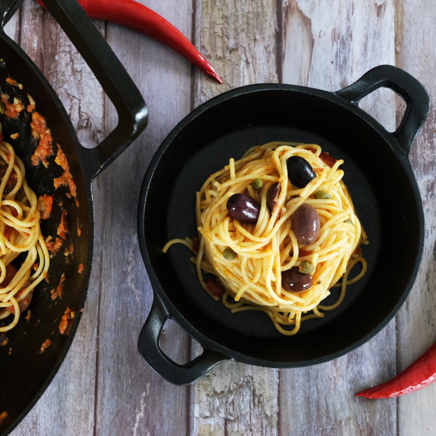 Cast-iron pan of spaghetti on a rustic wooden table
