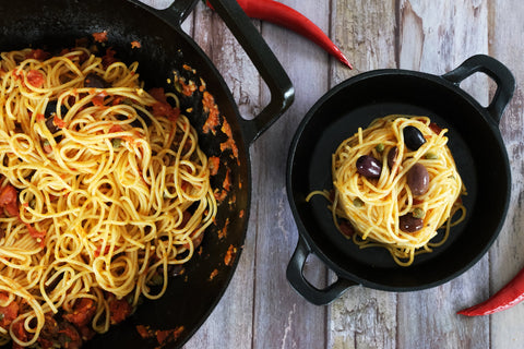Crucible Cookware cast iron skillets serving spaghetti on a rustic wooden table